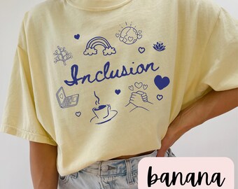 May include: A yellow t-shirt with a blue graphic design that says "Inclusion". The graphic includes a rainbow, a tree, a laptop, a coffee cup, a heart, a lotus flower, and a hand holding hands with another hand.