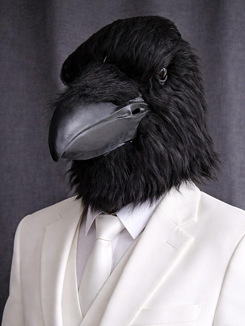 May include: A black raven mask with a large beak and feathery texture. The mask is worn with a white suit, vest, and tie. The suit has a classic, tailored fit. The background is a solid, neutral gray.