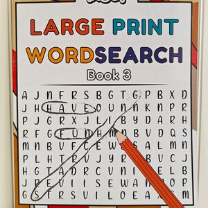 May include: A "Large Print Wordsearch Book 3" with the word "HAVE" circled and the word "FUN" circled. A pencil and a black pen are on the page. The book has a white background with a brown and orange border.