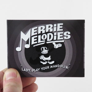 Może przedstawiać: Czarno-biała ilustracja postaci z kreskówki z nutą muzyczną na czarnym tle. Tekst "Merrie Melodies" jest napisany białymi literami nad postacią. Tekst "Lady, Play Your Mandolin!" jest napisany białymi literami pod postacią.