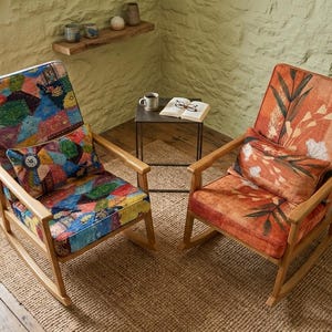 May include: Two wooden rocking chairs with patterned upholstery. One chair has a colourful patchwork design, the other an orange floral pattern. Both chairs have matching cushions and are set on a woven rug.