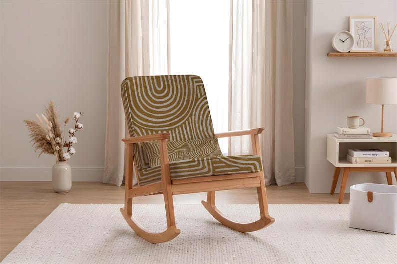 May include: A wooden rocking chair with a light brown frame and a seat and backrest upholstered in a green and white geometric pattern. The chair is placed on a white rug in front of a window.