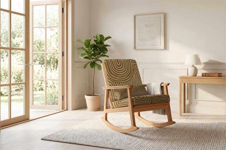 May include: A wooden rocking chair with a patterned seat and backrest. The chair has a light brown frame and is placed on a textured rug. A small side table with a lamp and a potted plant are also visible.