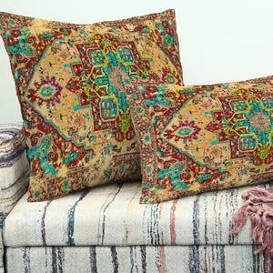 May include: Two decorative throw pillows with a vintage rug design in shades of beige, red, and teal. The pillows are rectangular and square, placed on a striped sofa. The design features geometric patterns.