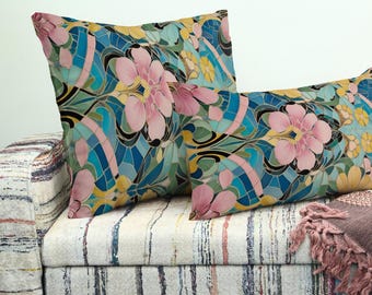 Può includere: Due cuscini decorativi con un motivo floreale. I cuscini presentano fiori rosa, accenti turchesi, blu e gialli su uno sfondo chiaro. I cuscini sono su un divano fantasia.