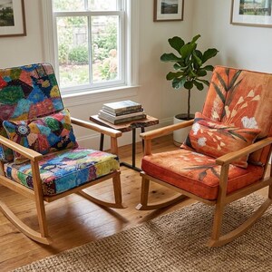 May include: Two wooden rocking chairs with patterned cushions and pillows. One chair features a patchwork design, the other an orange floral pattern. The chairs sit on a wooden floor with a woven rug.