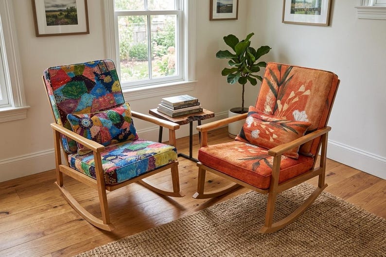 May include: Two wooden rocking chairs with patterned cushions and pillows. One chair features a patchwork design, the other an orange floral pattern. The chairs sit on a wooden floor with a woven rug.