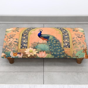 May include: Rectangular footstool with a vibrant peacock design. The peach-colored fabric features a peacock, lotus flowers, and other decorative elements. The wooden legs provide support. A decorative piece for any room.