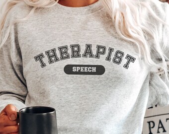 May include: A gray sweatshirt with the text "Therapist Speech" in a collegiate-style font.