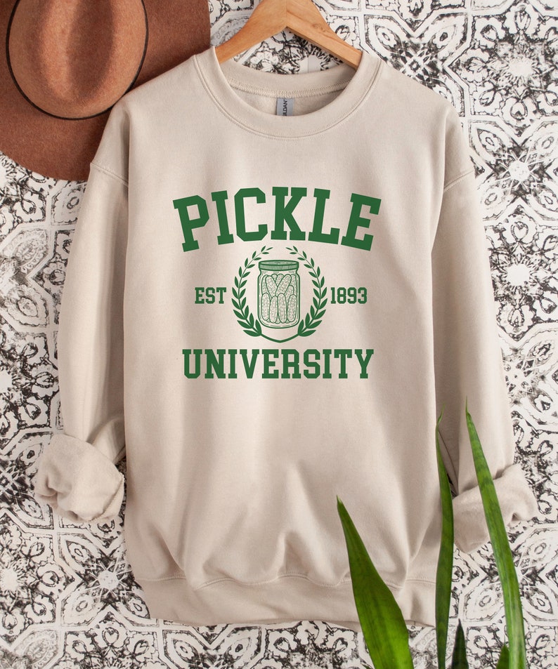 May include: A beige sweatshirt with a green graphic that says "Pickle University" with a pickle jar and the text "Est. 1893".