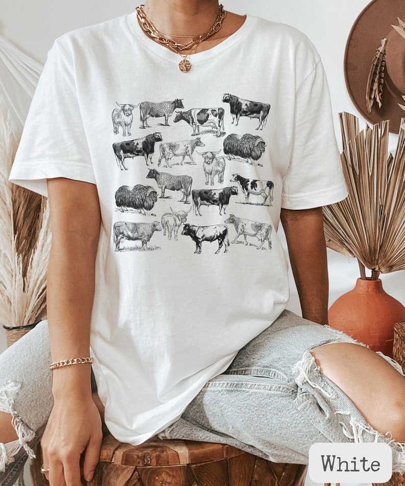 May include: White t-shirt with a graphic print of various breeds of cows. The shirt is oversized and has a relaxed fit.