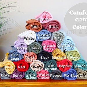 Puede incluir: Un conjunto de muestras de tela enrolladas en varios colores, incluyendo blanco, azul, rojo, verde, amarillo y marr&oacute;n. Las muestras de tela est&aacute;n etiquetadas con nombres como "Blossom", "Yam", "Brick", "Washed Denim", "Bay", "Orchid", "Moss", "Crunch Berry", "Chambray", "Terra Cotta", "Black", "Mustard", "Celadon", "Butter", "Red", "Ivory", "Blue Spruce", "Paprika", "Seafoam", "Grey", "Berry", "Light Green", "Watermelon", "Pepper", "Flo Blue" y "Khaki". El texto "Comfort C1717 Colors" es visible en la parte superior de la imagen.