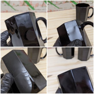 May include: Set of four black glass mugs with a hexagonal shape and a handle. The mugs have a glossy finish and are perfect for serving beverages.