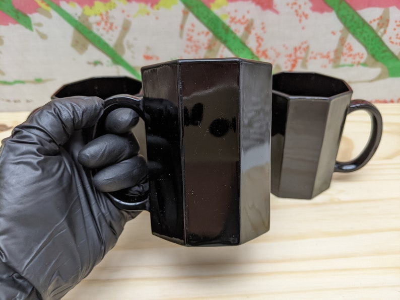 May include: Three black octagonal mugs with handles. The mugs are made of glass and have a shiny finish.