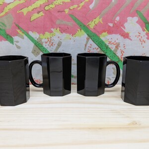 May include: Set of four black octagonal mugs with handles. The mugs are made of glass and have a shiny finish.