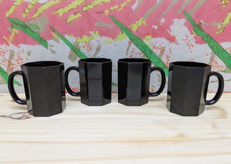 May include: Set of four black octagonal mugs with handles. The mugs are made of glass and have a shiny finish.