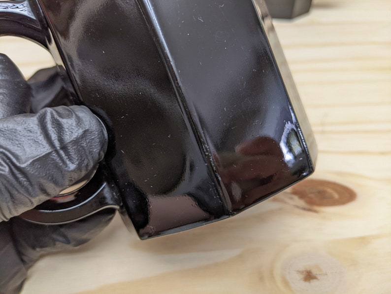 May include: A black ceramic mug with a handle. The mug has a glossy finish and is slightly chipped on the edge.