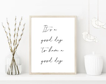 May include: A framed print with the text "It's a good day to have a good day" in black script. The image includes a glass vase with branches, a white jar, and hanging bird decorations.