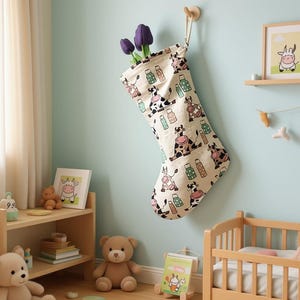 Könnte beinhalten: Ein cremefarbener Weihnachtsstrumpf mit Kuhmuster hängt an einer Wand. Der Strumpf ist mit lila Tulpen gefüllt. Der Raum hat eine hellblaue Wand, ein Holzregal und ein kleines Holzbett. Ein gerahmtes Bild einer Kuh befindet sich auf dem Regal.