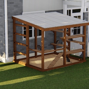May include: A wooden cat enclosure with a sloped roof and multiple levels for climbing and lounging. The structure is made of brown wood and wire mesh, with a ramp and platforms. Several cats are inside the enclosure.