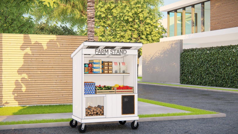 May include: A white farm stand on wheels with the text "FARM STAND" on top. The stand is stocked with various groceries, including eggs, produce, and packaged goods. A small chalkboard is on the side. The stand is outdoors, near a residential area.