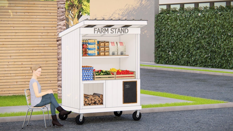 May include: A white farm stand on wheels with the text "FARM STAND" on top. The stand displays various products, including eggs, produce, and packaged goods. A person sits on a chair next to the stand.