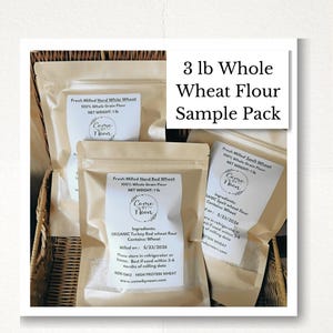 May include: Three stand-up pouches of whole grain flour, each labeled with the Come By Noon logo. The labels specify Fresh Milled Hard White Wheat, Hard Red Wheat, and Spelt Wheat, each with a net weight of 1 lb. The text 3 lb Whole Wheat Flour Sample Pack is visible.