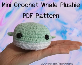 May include: A crochet whale plushie pattern in PDF format. The plushie is green and white and has a cute, cartoon-like face. The image shows the plushie in a hand, with a website address for the Etsy shop in the bottom right corner.