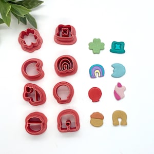 May include: A set of 12 red plastic cookie cutters in various shapes, including a flower, horseshoe, rainbow, and a hat. There are also 6 small colorful fondant decorations in various shapes, including a rainbow, a clover, and a hat.