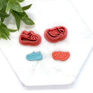 May include: Four plastic cookie cutters shaped like sandals. Two are red with white polka dots, one is blue with white polka dots, and one is red with white polka dots.