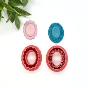 May include: Four cookie cutters in the shape of oval frames. Two are red with a scalloped edge and two are solid, one pink and one teal.