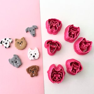 May include: A set of nine dog-shaped cookie cutters, including a pug, a dachshund, a terrier, a greyhound, a bulldog, a poodle, a labrador, a chihuahua, and a Yorkshire terrier. The cutters are pink and have a shiny finish.