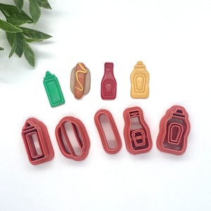 May include: Set of nine red and brown plastic cookie cutters shaped like hot dogs, buns, ketchup bottles, mustard bottles, and relish bottles.