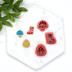 May include: Set of six red and yellow plastic cookie cutters shaped like rain boots, umbrellas, and raincoats.