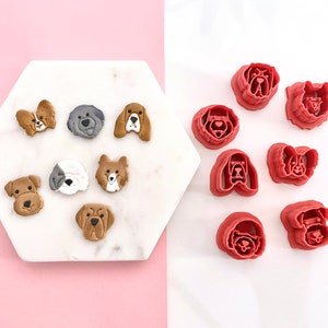 May include: A set of 10 red plastic dog-shaped cookie cutters. The cutters are arranged in two rows on a white surface. The cutters are all different breeds of dogs, including a bulldog, a dachshund, a poodle, and a labrador.