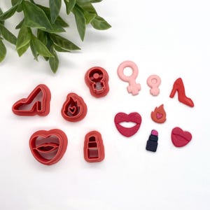 May include: A set of 11 red and pink plastic cookie cutters shaped like lips, a high heel shoe, a lipstick tube, a flame, a heart, and the female gender symbol.