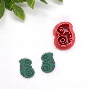 May include: Two green chameleon cookie cutters with colorful details and a red chameleon cookie cutter.