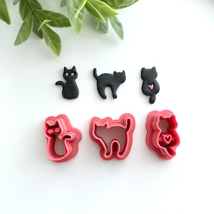 May include: Set of six black and pink cat cookie cutters. The cutters are in the shape of a cat sitting, a cat standing, and a cat with a heart.