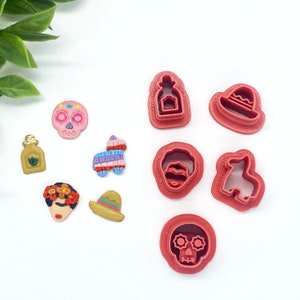 May include: A set of ten red plastic cookie cutters featuring various Mexican-themed designs, including a skull, a bottle of tequila, a sombrero, a pinata, a donkey, and a Frida Kahlo portrait.