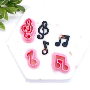 May include: Set of five pink and black plastic cookie cutters shaped like musical notes and treble clefs.