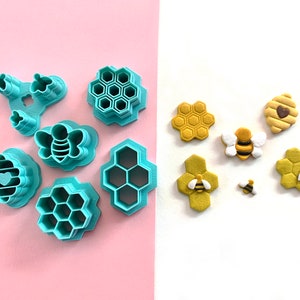 May include: A set of teal-coloured cookie cutters shaped like honeycombs and bees, and a set of yellow fondant decorations shaped like honeycombs and bees.