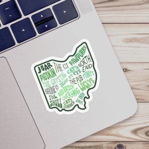 May include: A green and white sticker shaped like the state of Ohio with the names of bars and pubs in Columbus, Ohio. The sticker includes the text "JBAR, Pigskin, The CI Pawpurrs, The Crystal, Cat's North, Broneys, Jackie O's Eye End, The Pub Tony's, Red Bride, The Overhang, Luckys, Cats Corner, Win".