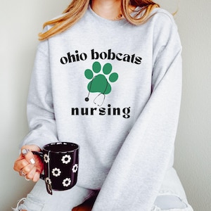May include: A gray sweatshirt with the text "ohio bobcats nursing" and a green paw print with a stethoscope.