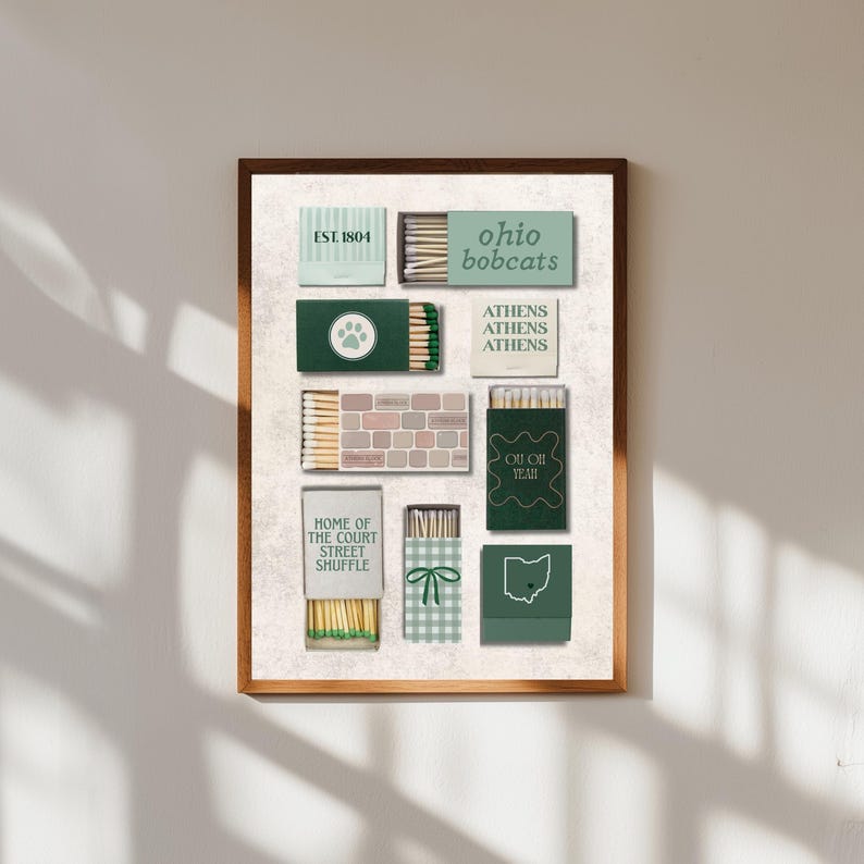 Puede incluir: Un estampado enmarcado con varios dise&ntilde;os de cajas de cerillas. Las cajas son en tonos verdes, beige y blanco, con textos como "Ohio Bobcats", "Athens" y "Home of the Court Street Shuffle". El estampado tiene un fondo neutro.
