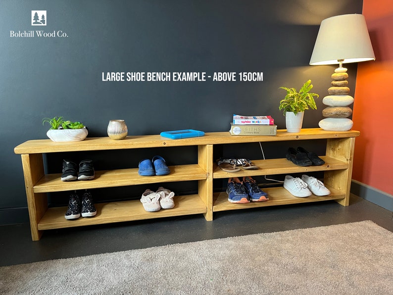 May include: A wooden shoe bench with three shelves, holding various shoes and a few books. The bench is 150cm long and is made by Bolehill Wood Co.