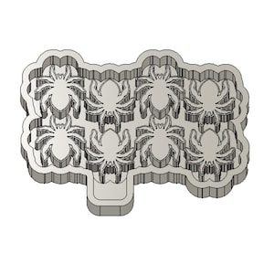 Può includere: Un tagliapasta di plastica grigia a forma di nuvola con otto ragni all'interno.