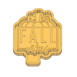 May include: A yellow cookie cutter shaped like a pumpkin with the words "FALL vibes" inside a rectangle.