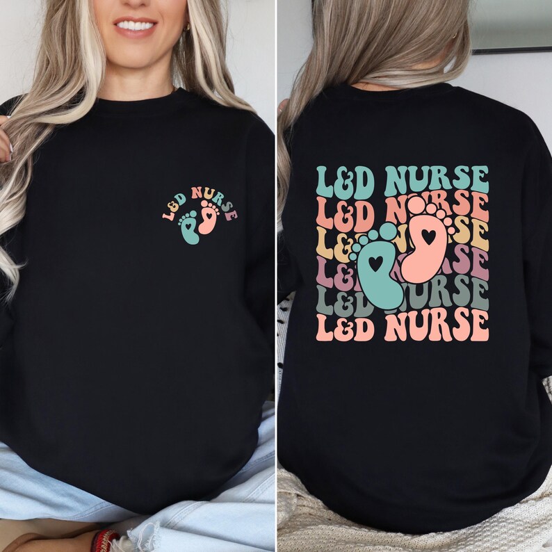 May include: Black sweatshirt with a graphic of a pair of baby footprints and the text "L&D NURSE" on the front. The back of the sweatshirt has the text "L&D NURSE" repeated in a stacked, retro design with a pair of baby footprints in the center.