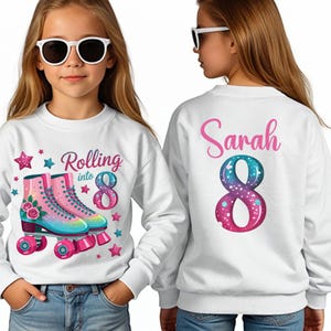 May include: White sweatshirt featuring the text "Rolling into 8" and a pair of colourful roller skates. The number 8 has a galaxy design. The back of the sweatshirt has the name "Sarah" and a galaxy-themed number 8.
