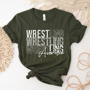 May include: A green t-shirt with the text "Wrestling Auntie" in white with a distressed look.